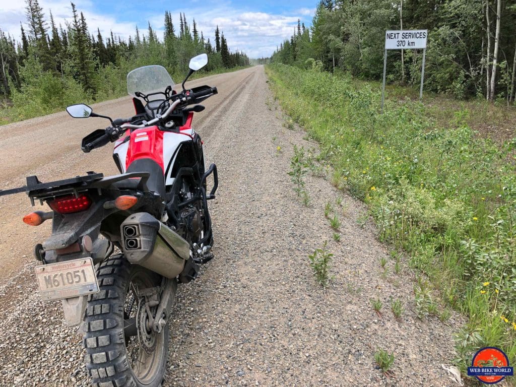 Honda Africa Twin on the Dempster Highway with a warning sign. 370 kms to the next gas station.