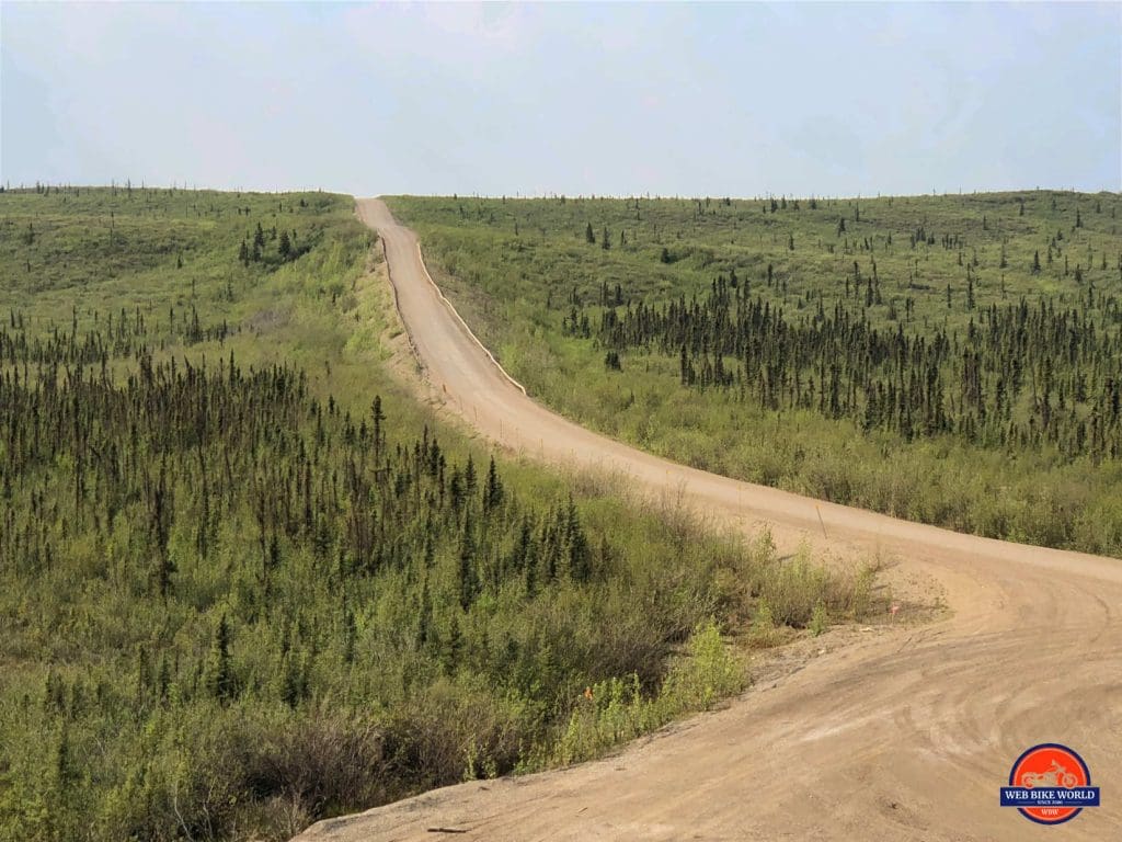 The dusty Dempster Highway surrounded by forest.