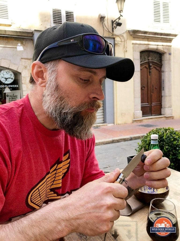 Eating an olive using an Opinel knife in Grasse, France.