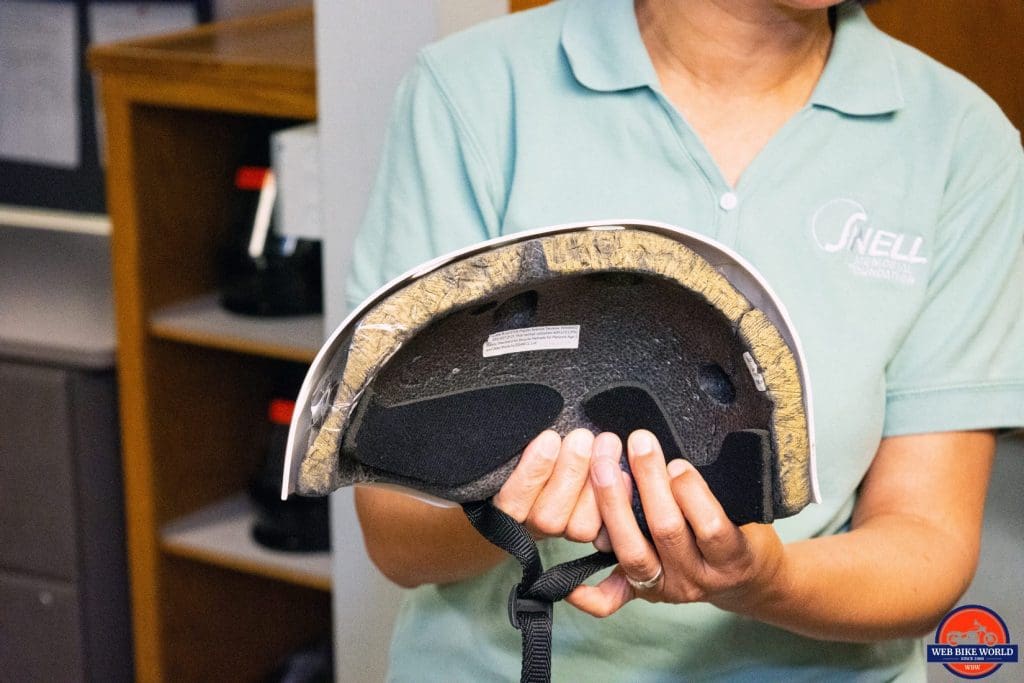 Hong Zhang showing a cutaway model of EPS foam inside a helmet that has been dented by impacts.