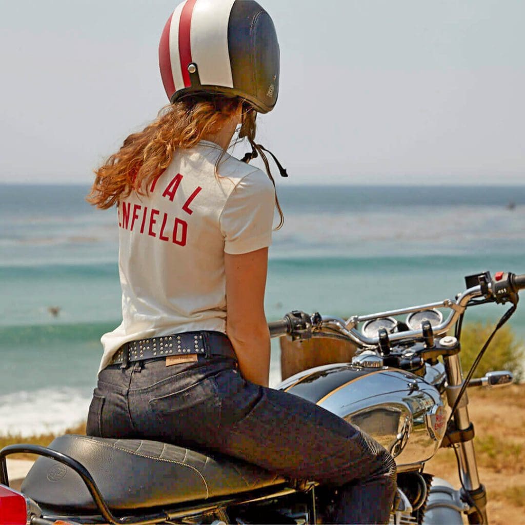 A woman sitting on a Royal Enfield motorcycle.