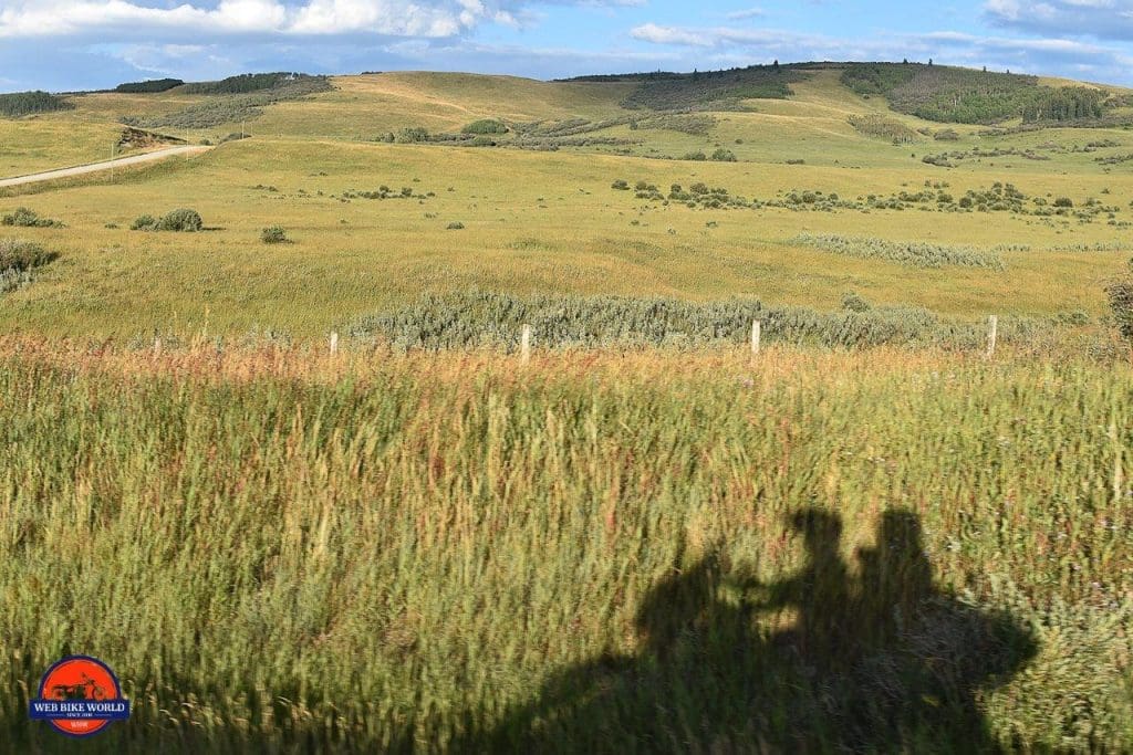 The shadow of a motorcycle with riders on the grass near Longview, Alberta.