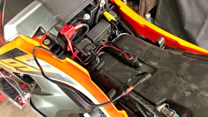 The 12V battery harness connected to the battery terminals on a KTM 790 Adventure.