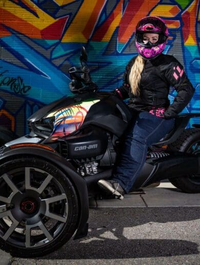 Writer Brittany Morrow on the Can-Am Ryker 900 Rally Edition in front of graffiti wall.
