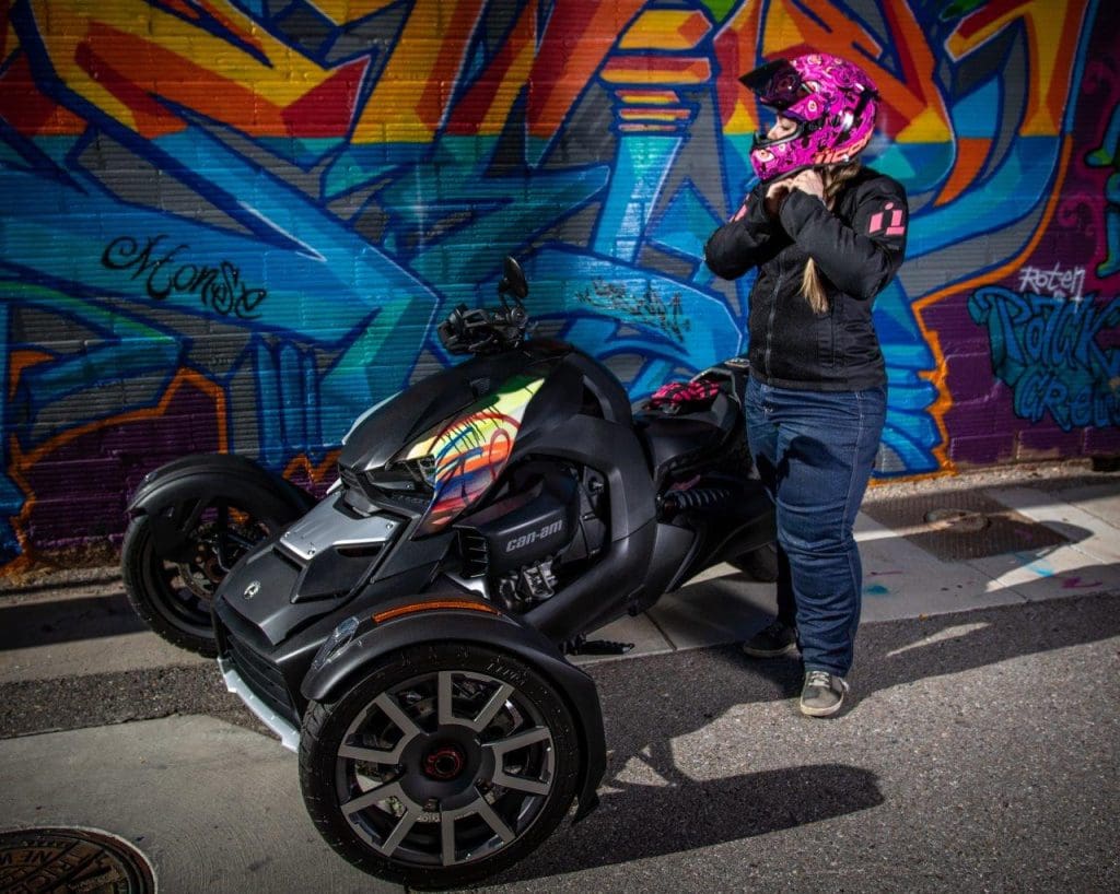 Rider adjusting her helmet next to Can-Am Ryker 900 Rally Edition