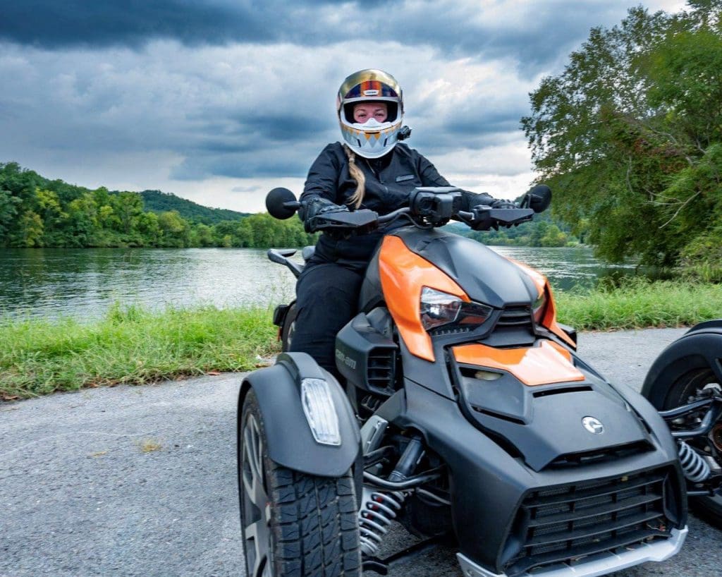 Rider on Can-Am Ryker 900 Rally Edition with lake behind her.