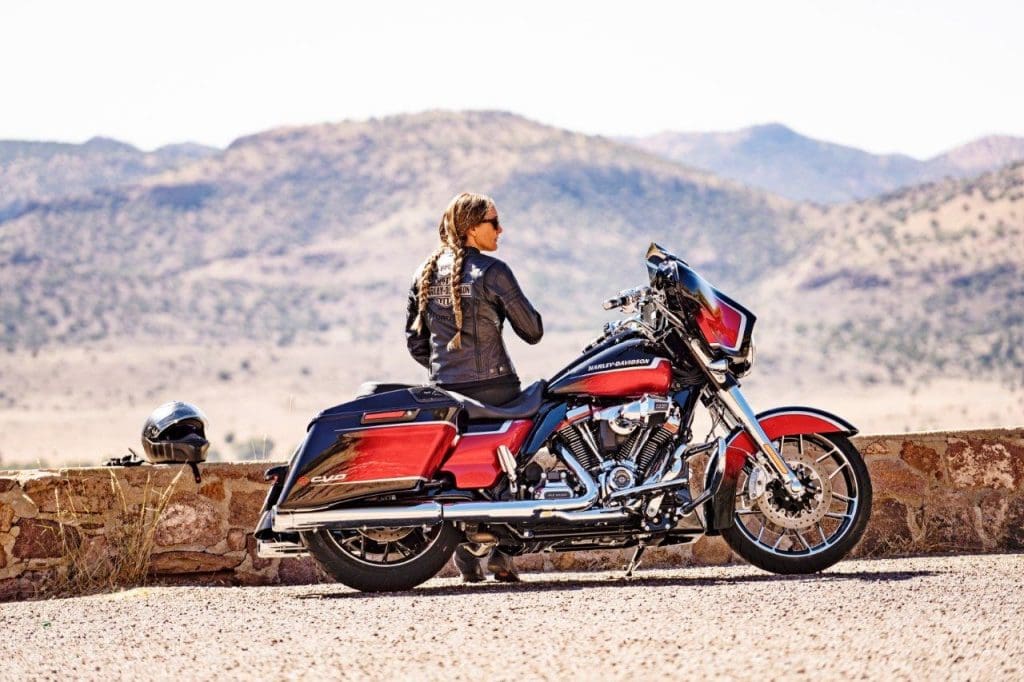 A woman rider sitting with her 2021 Harley Davidson Street Glide CVO.