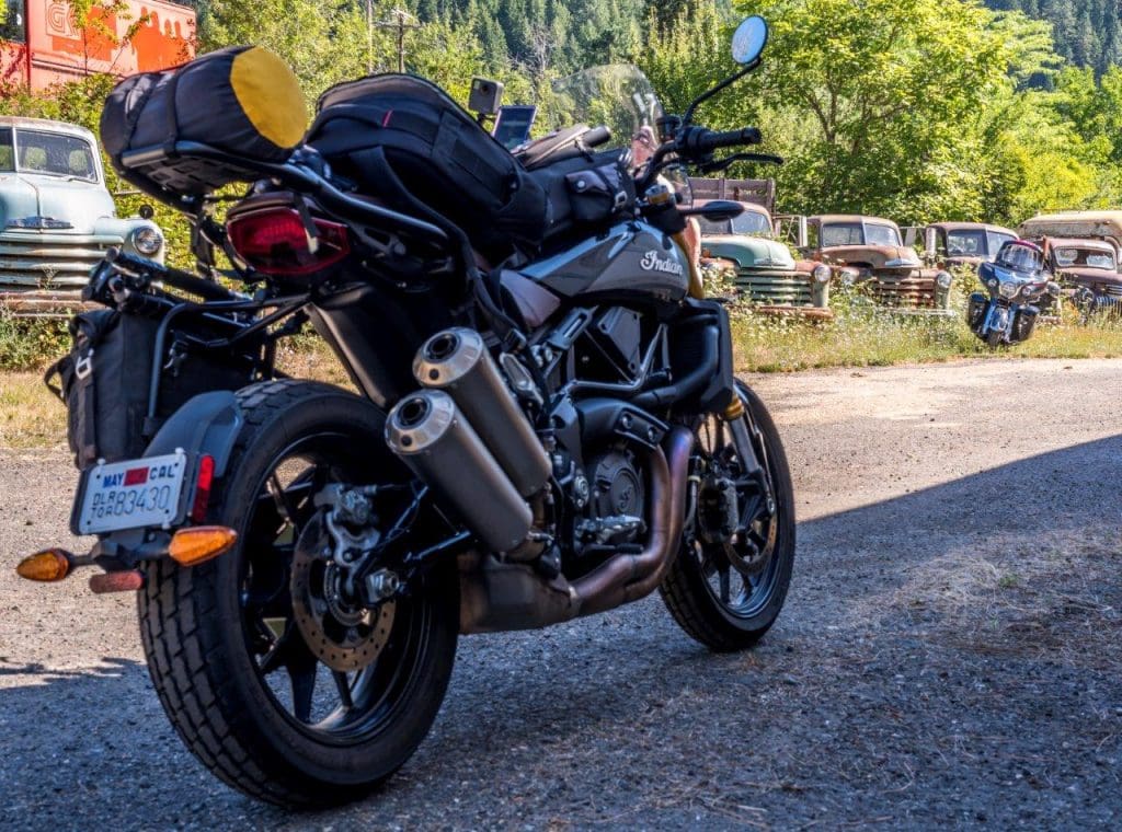 Indian FTR 1200 S with Touring Accessory package parked on a gravel road with old pickup trucks in Montana