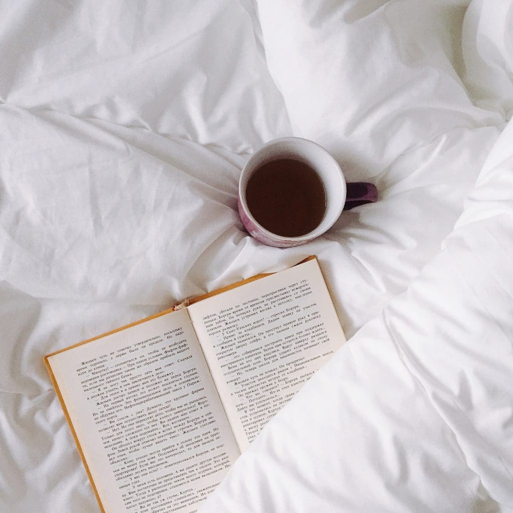 Book and coffee cup on bed