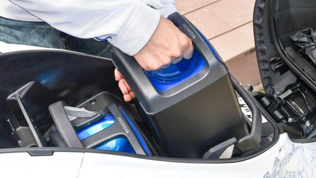 battery being placed in a vehicle likely make by Honda, Yamaha, Suzuki or Kawasaki