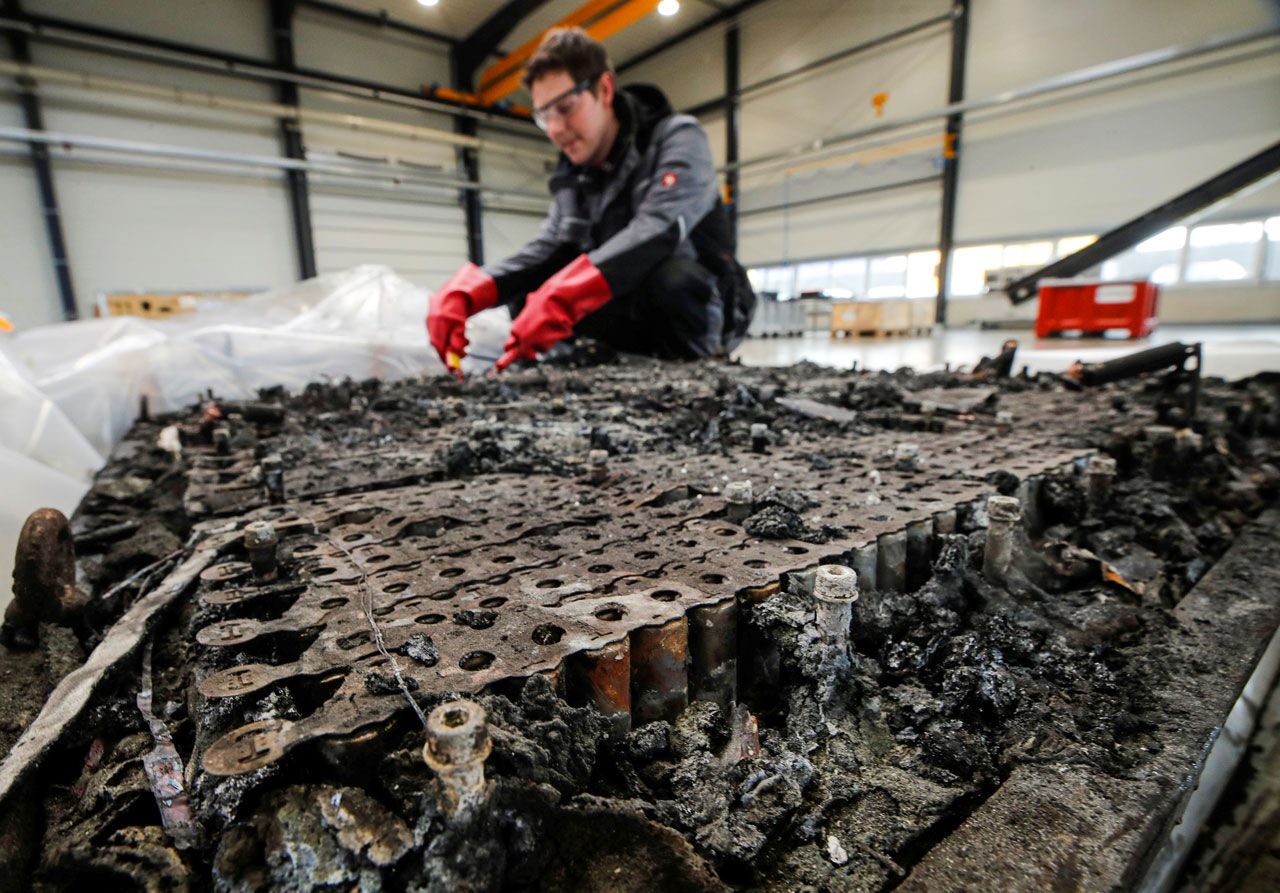 A technician checks the possible remaining voltage of a completely burned Lithium-ion car battery before its dismantling by the German recycling firm Accurec in Krefeld