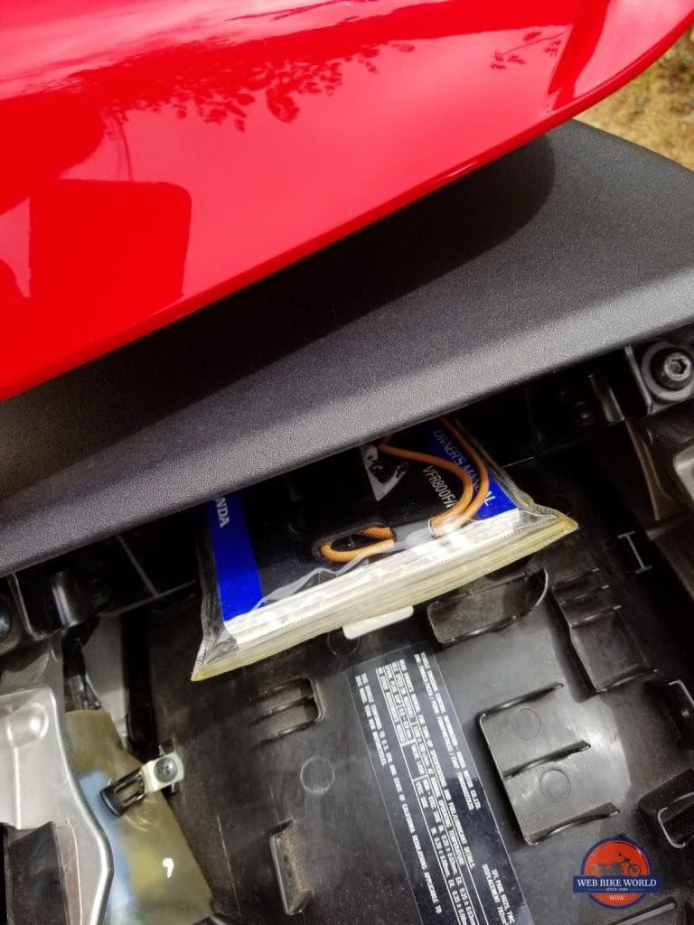 GPS tracker in the vinyl bag of owners manual stored in the slot of tail storage