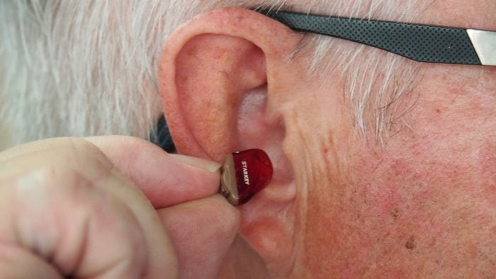 A man inserting a hearing aid A man inserting a hearing aid