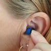 A woman inserting an earplug
