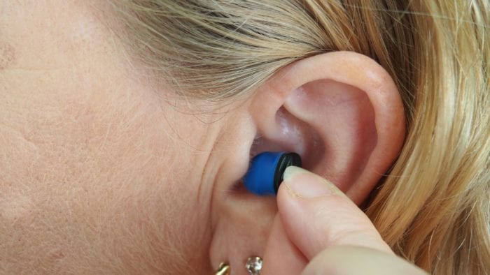 A woman inserting an earplug A woman inserting an earplug