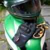 Pitlane gloves and helmet sitting on top of motorcycle fuel tank