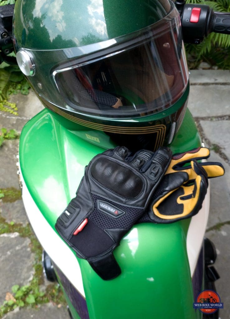 Pitlane gloves and helmet sitting on top of motorcycle fuel tank