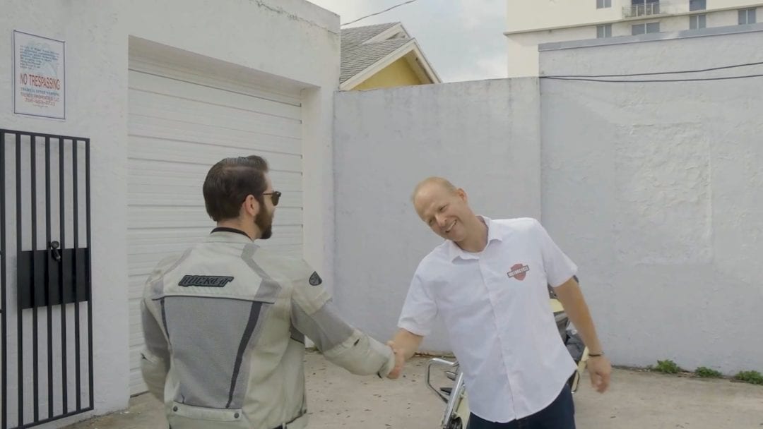 two men in a business deal, shaking hands - likely affiliated with the new Riders Share incentive towards their motorcycle rental program