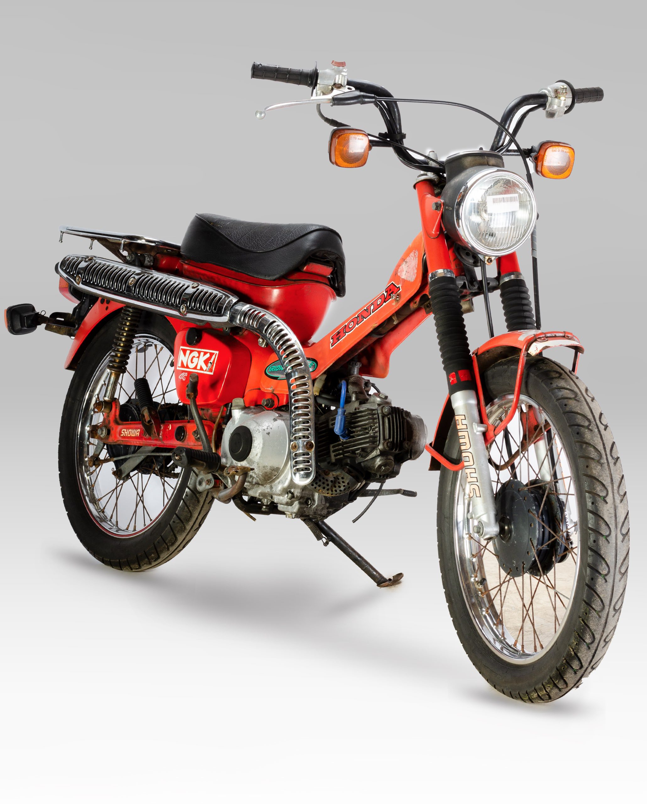 A Honda CT110 'Postie' bike in a studio