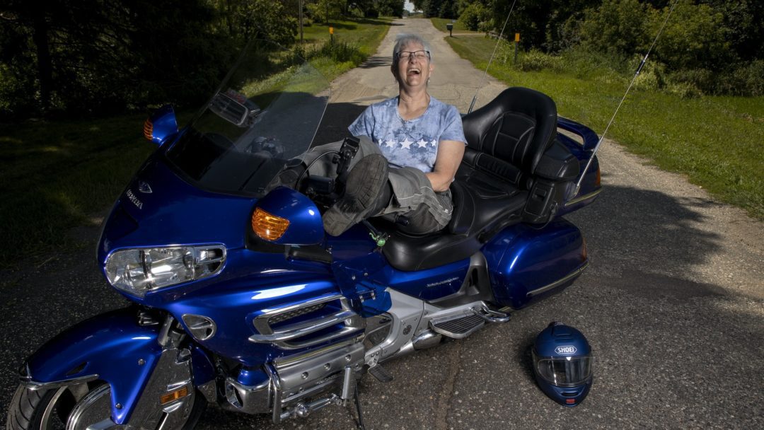 a woman leans across her motorcycle as she gets ready to ride at the three women ride for the Suffragists Centennial Motorcycle Ride