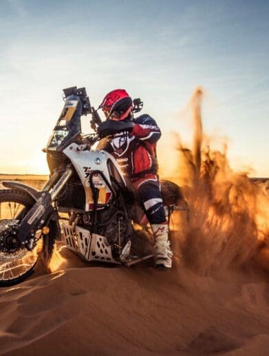 A view of a racer in the 1000 Dunas raid traversing desert dunes on a sunny day