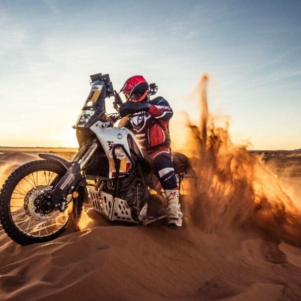 A view of a racer in the 1000 Dunas raid traversing desert dunes on a sunny day