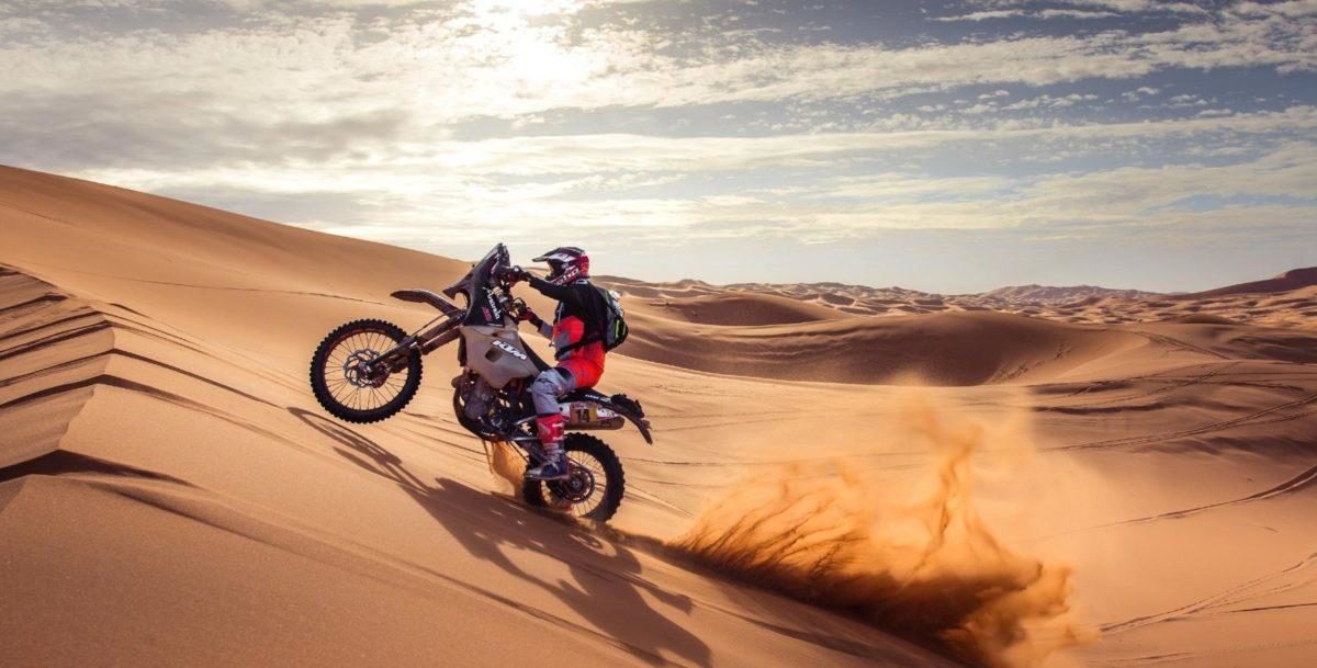A view of a racer in the 1000 Dunas raid traversing desert dunes on a sunny day