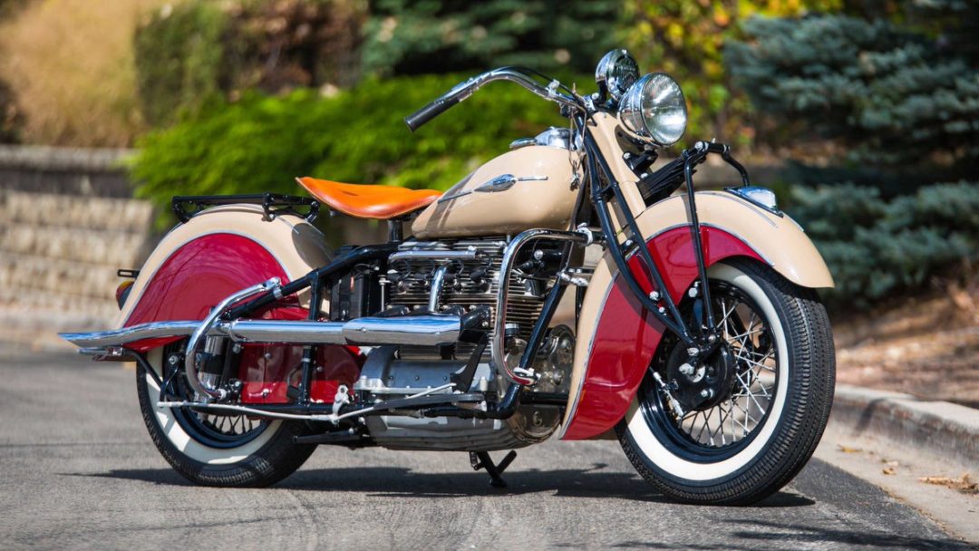 a view of a 1941 Indian Four, on pavement, with verdure in the background.