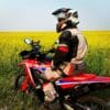 Me sitting on my 2021 Honda CRF300L Rally ABS in front of a canola field.