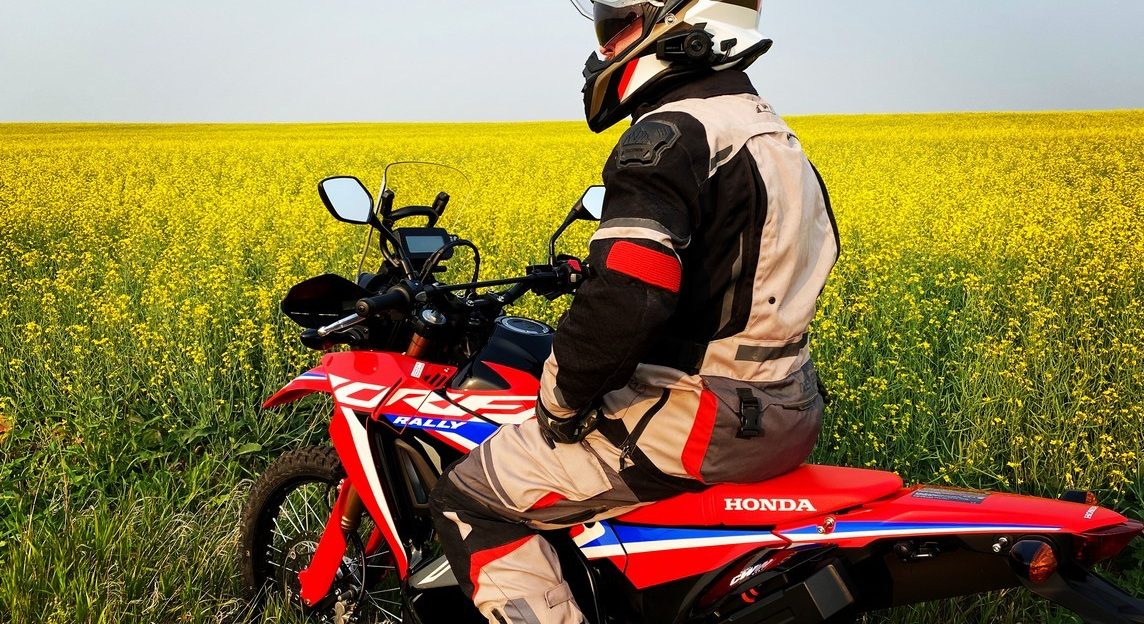 Me sitting on my 2021 Honda CRF300L Rally ABS in front of a canola field.