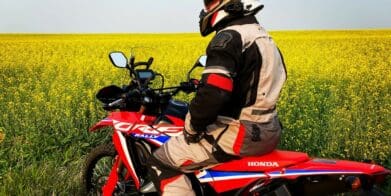Me sitting on my 2021 Honda CRF300L Rally ABS in front of a canola field.