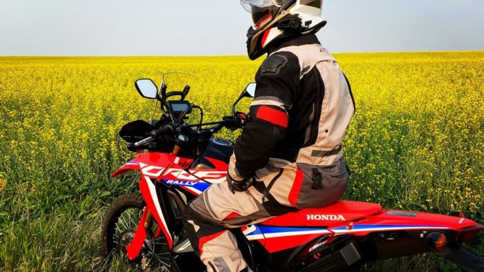 Me sitting on my 2021 Honda CRF300L Rally ABS in front of a canola field.