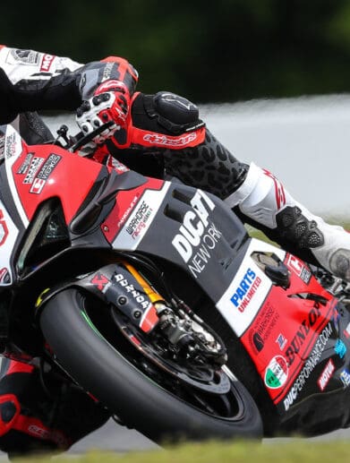 A front view of Loris Baz at the MotoAmerica Superbike Championship, leaning into a turn.