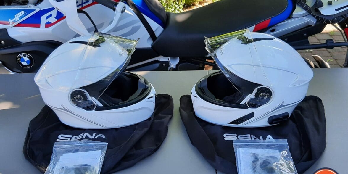 A view of two Outrush R Modular Helmets, in front of a BMW Motorcycle