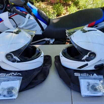 A view of two Outrush R Modular Helmets, in front of a BMW Motorcycle