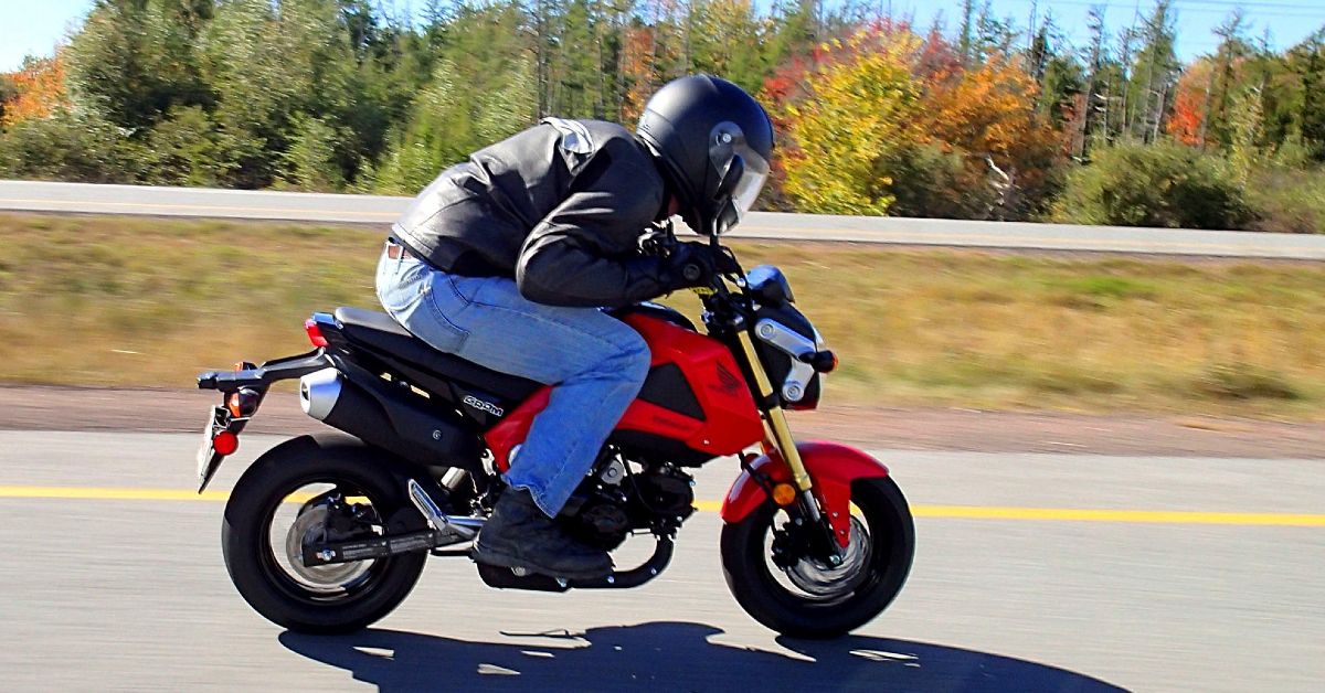 A view of a rider leaning over the handlebars of a Honda Grom.