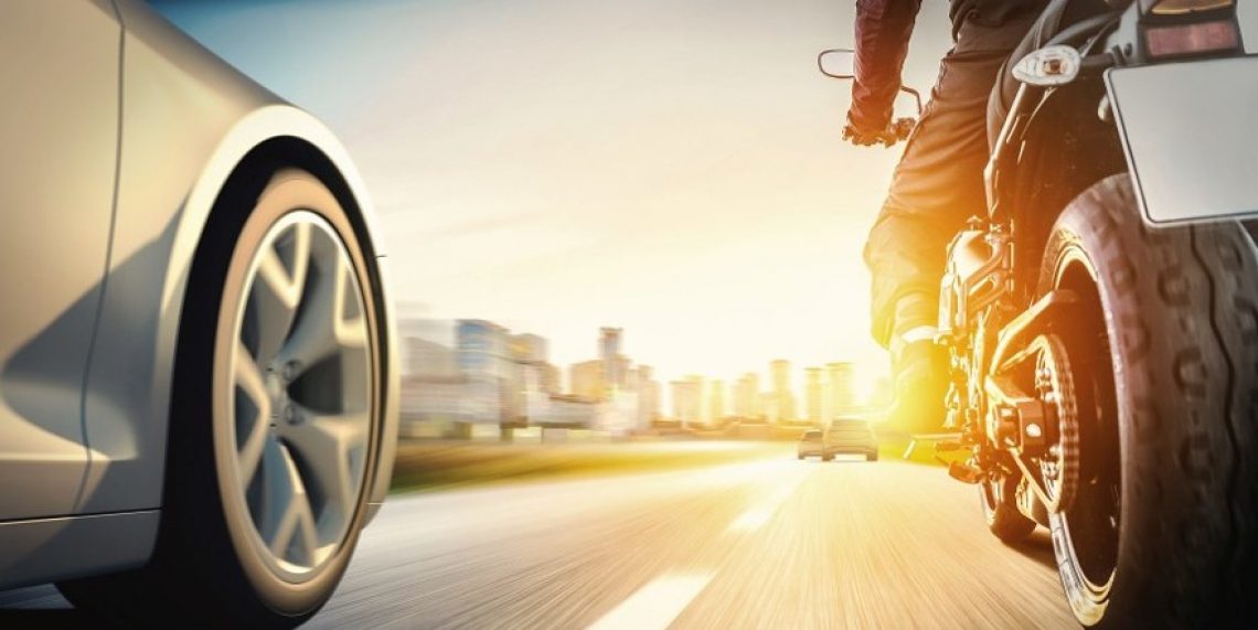 A motorcyclist and car sharing the same road