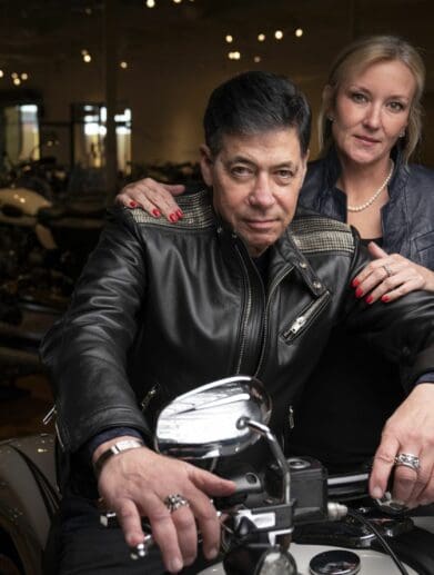 Robert Haas and partner as he sits on one of the motorcycles in his (Haas) Moto Museum