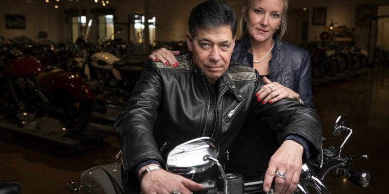 Robert Haas and partner as he sits on one of the motorcycles in his (Haas) Moto Museum