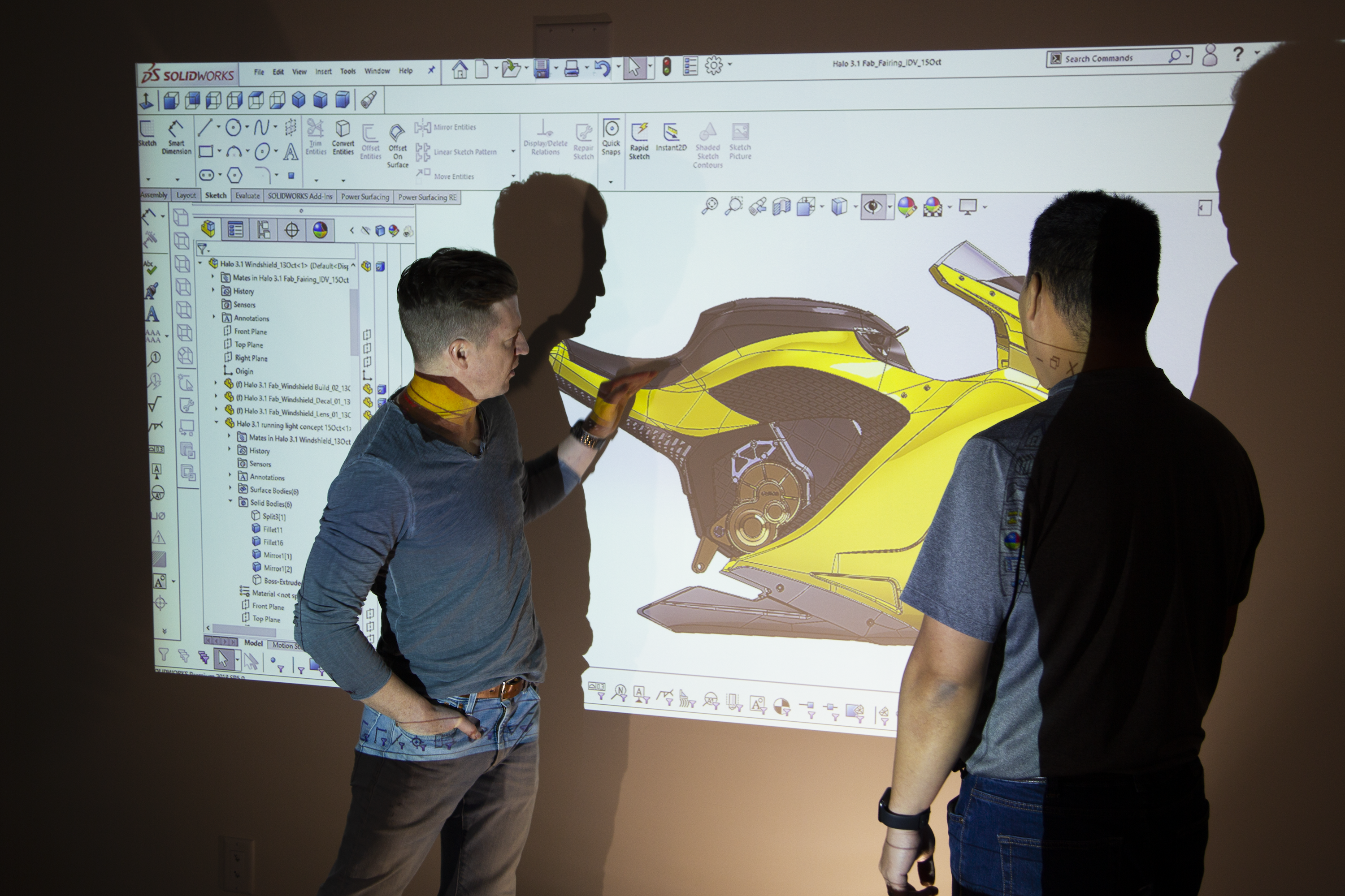 A projector screen showing the Damon HyperSport with CEO Jay Jiraud indicating certain features