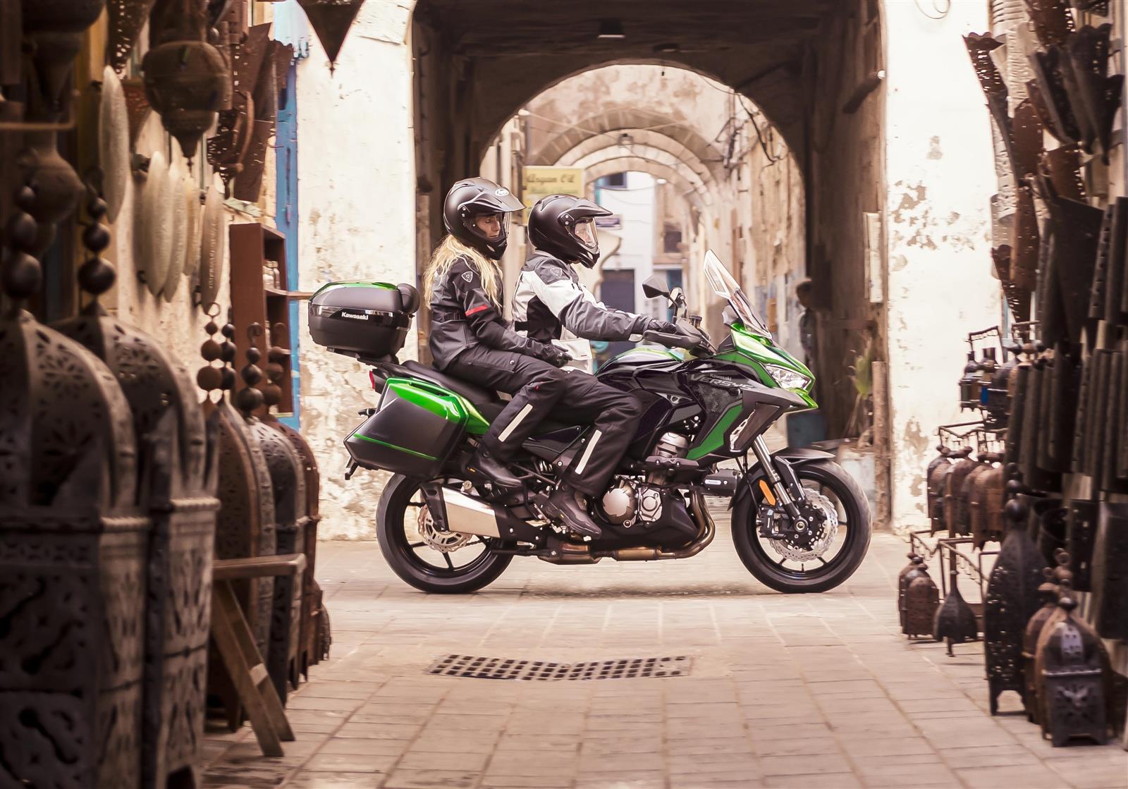 Rider and pillion on the Kawasaki Versys 1000 riding through a narrow street