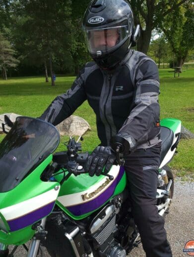 Man wearing Richa Airstorm WP Jacket while sitting on green Kawasaki motorcycle