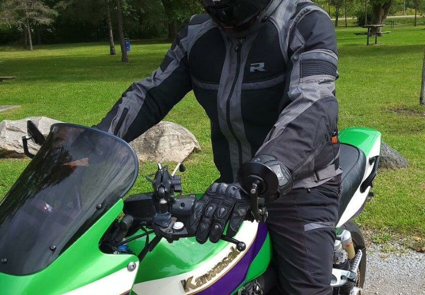 Man wearing Richa Airstorm WP Jacket while sitting on green Kawasaki motorcycle
