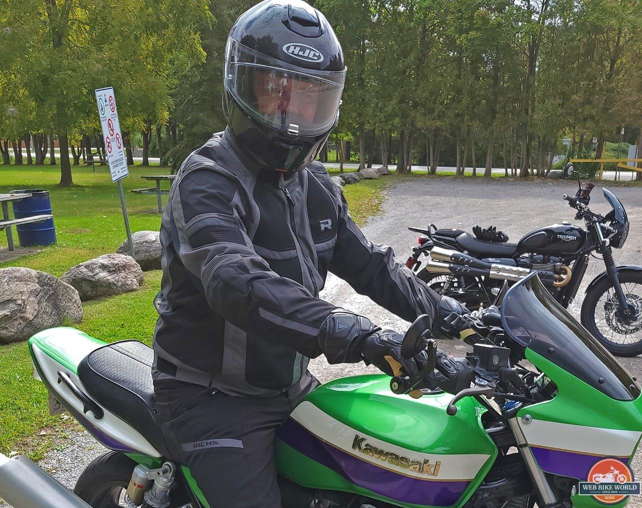 Man wearing the Richa Airstorm WP Jacket while sitting on green Kawasaki motorcycle