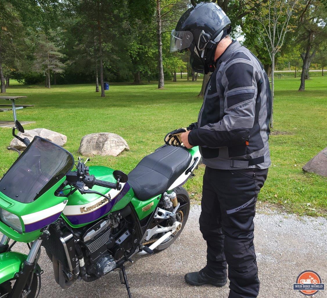 Rider wearing Richa Softshell WP Pants standing next to Kawasaki motorcycle