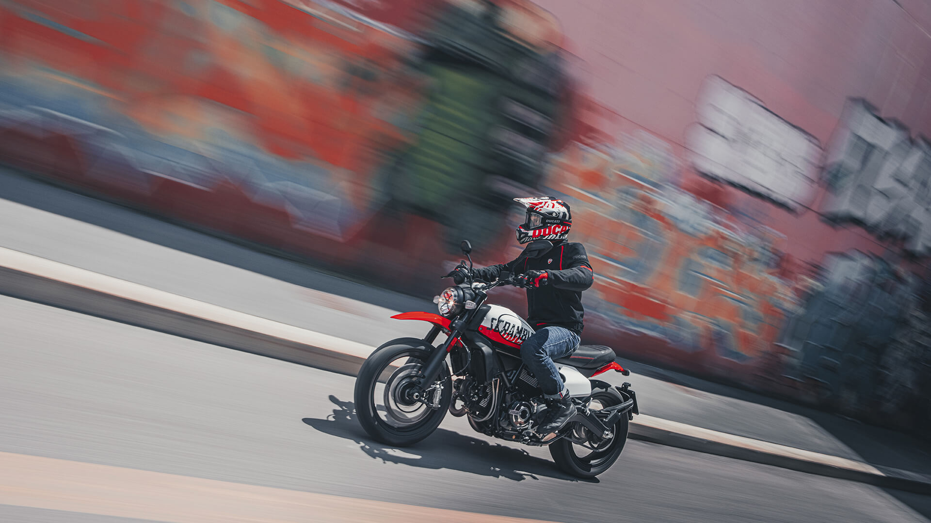 A side view of a model trying out the new Scrambler Ducati Urban Motorcycle courtesy of Ducati's World Premiere