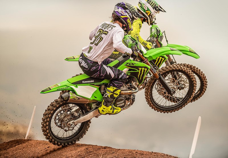 A side profile of two riders trying out the new 2022 Kawasaki KX450SR edition on a dirt track