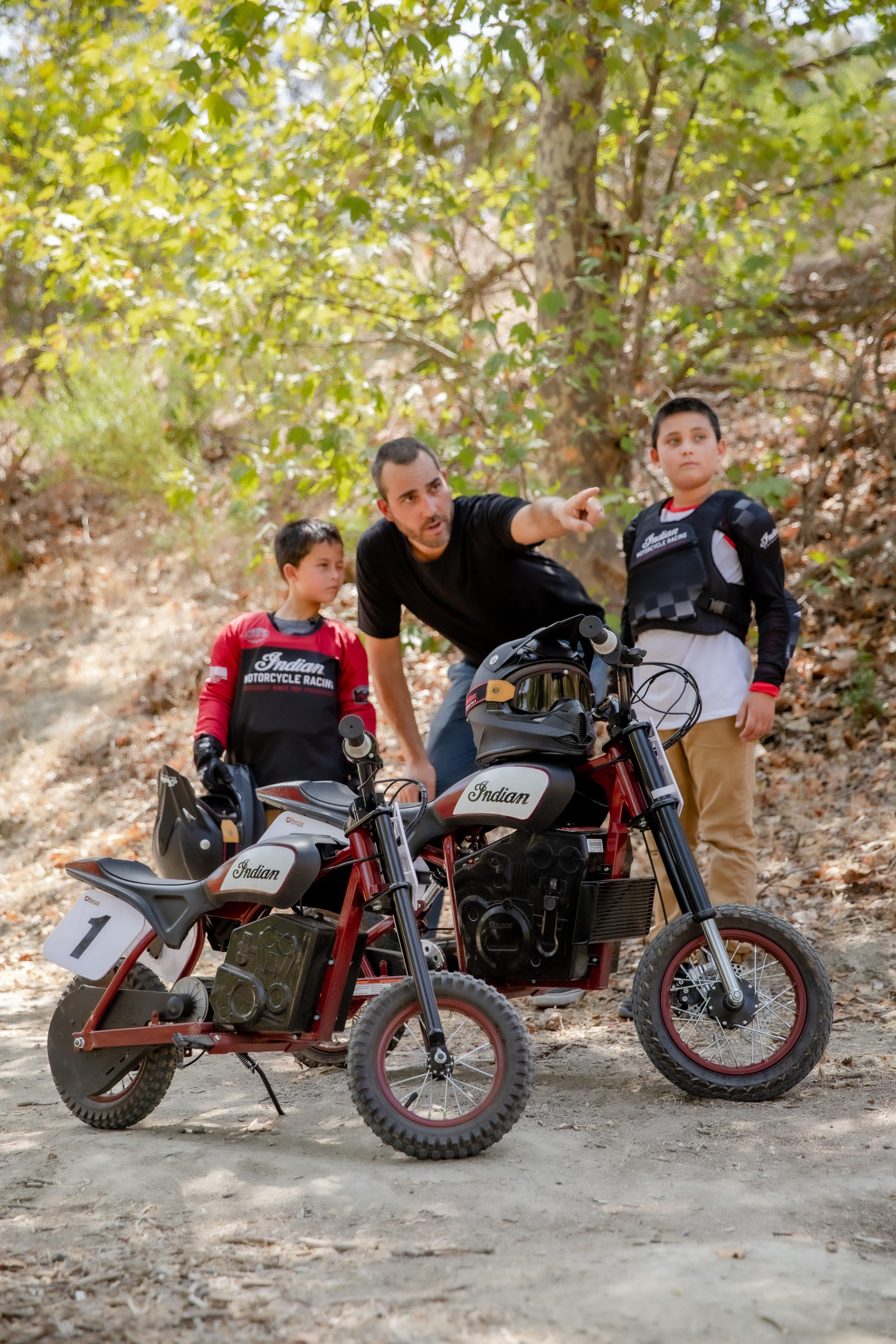 A view of a mature rider with two younger riders trying out the new sFTR Mini motorcycles from Indian Motorcycles - an electric-youth bike available to the smaller riding community