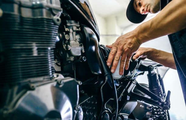 Mechanic repairing customized motorcycle in the workshop