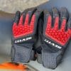 REV'IT Sand 4 Gloves in black and red lying next to each other on motorcycle seat